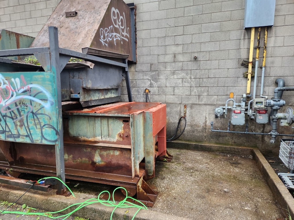 Clean compactor pad beside commercial facility equipment after service