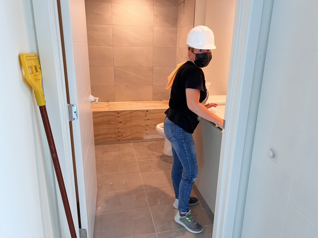 Post-construction cleaner detailing a bathroom in a new apartment