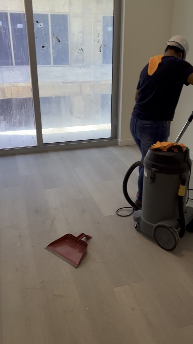 Worker using an industrial vacuum during apartment post-construction cleaning