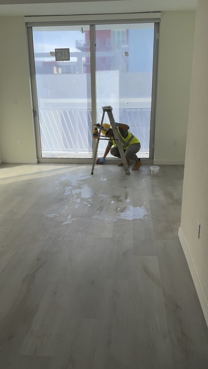 Worker washing an apartment floor during post-construction cleaning