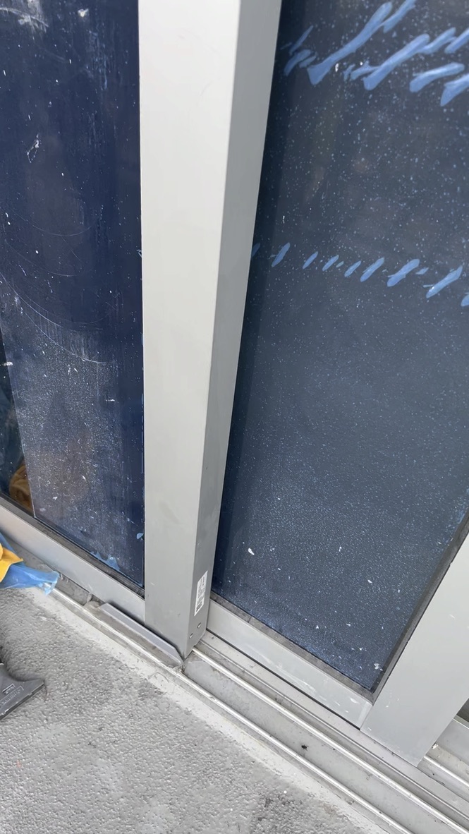 Construction dust, paint marks and residue on apartment sliding glass before cleaning