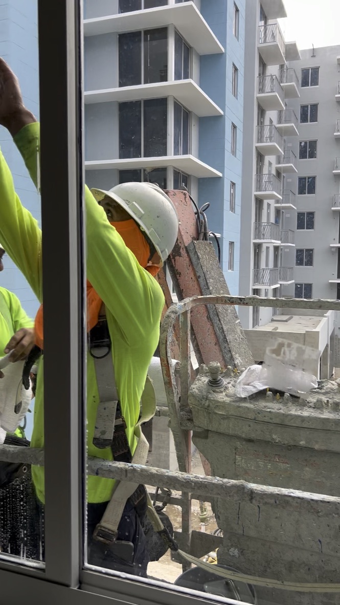 Technician detailing apartment glass and window edges from a lift